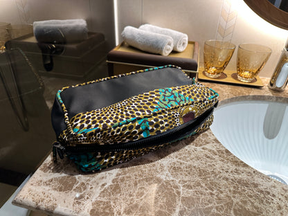 Afia Okra Splash African Print Wash Bag, located at the side of a handbasin, rolled hand towels, glass tumblers and a brass mixer tap. 
