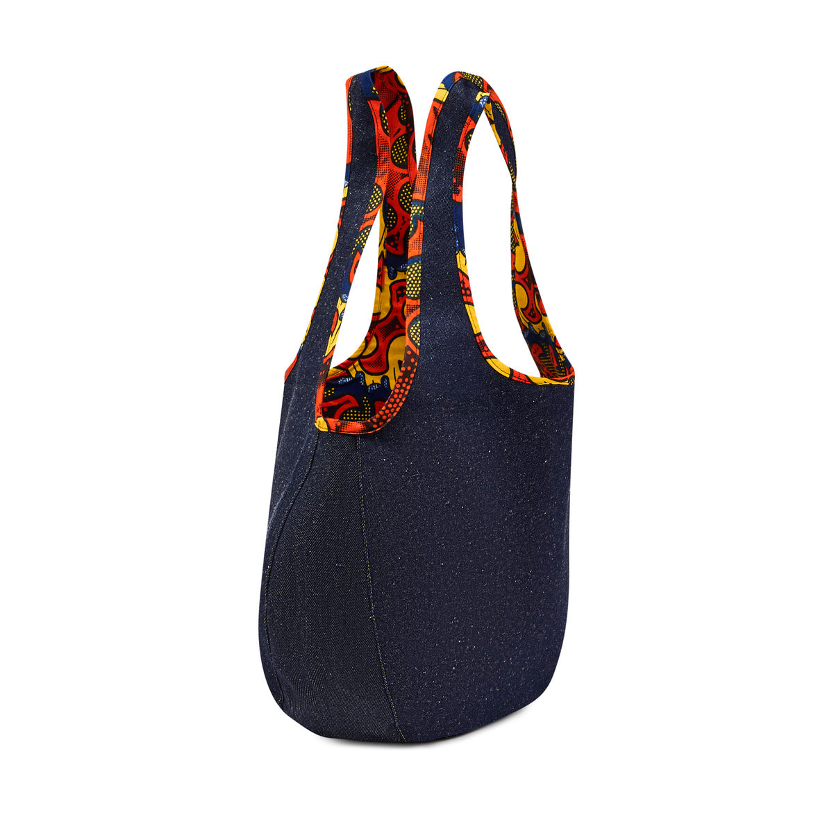 Side profile of the Kalia Denim reversible Hobo bag lined with Zumba African 
printed fabric, and Zumba African printed fabric piping around the handles against a white back ground.