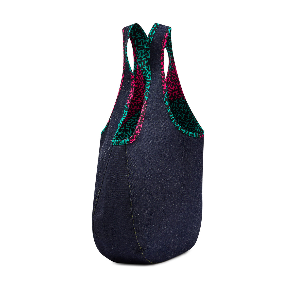 Side profile of the Kalia Denim reversible Hobo bag lined with Jollof Pink African printed fabric, and Jollof Pink African printed fabric piping around the handles against a white back ground.