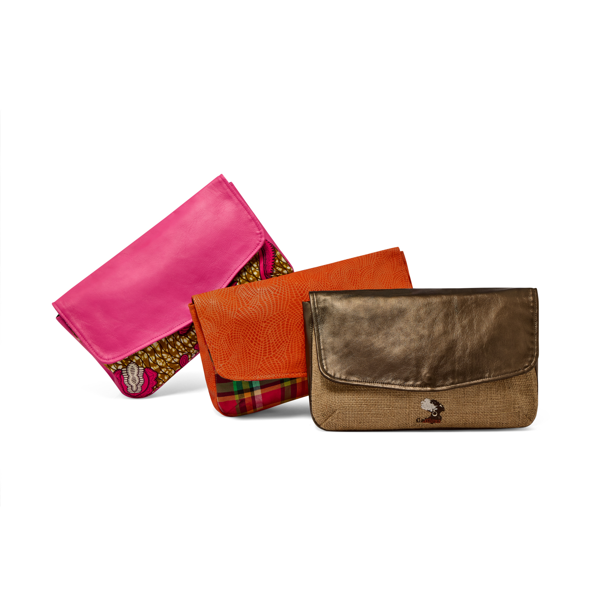 A collection of three Mahalia clutches in pink leather & Pink Paisley African printed fabric, orange leather and Antigua & Barbuda Madras fabric, and Metallic bronze leather with Natural hessian fabric displayed against a white background.